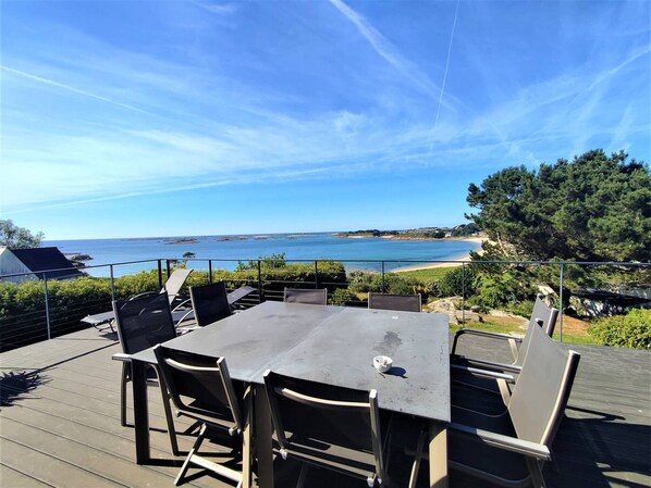 A deck with a table and chairs overlooking a beach. - Beachfront house in Trébeurden with garden and terrace (Trébeurden)