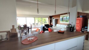 A modern kitchen with a central island, dining area with chairs, and a sofa. - Beachfront house in Trébeurden with garden and terrace (Trébeurden)