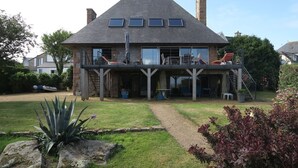 A two-story house with a balcony, a covered patio, and a garden with rocks and plants. - Beachfront house in Trébeurden with garden and terrace (Trébeurden)