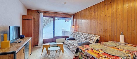 A cozy room with a bed, a desk, a chair, and a window with a view of the outdoors.