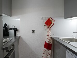 Eine Küche mit Spüle aus Edelstahl, einer Kaffeemaschine und einem kleinen Fenster.