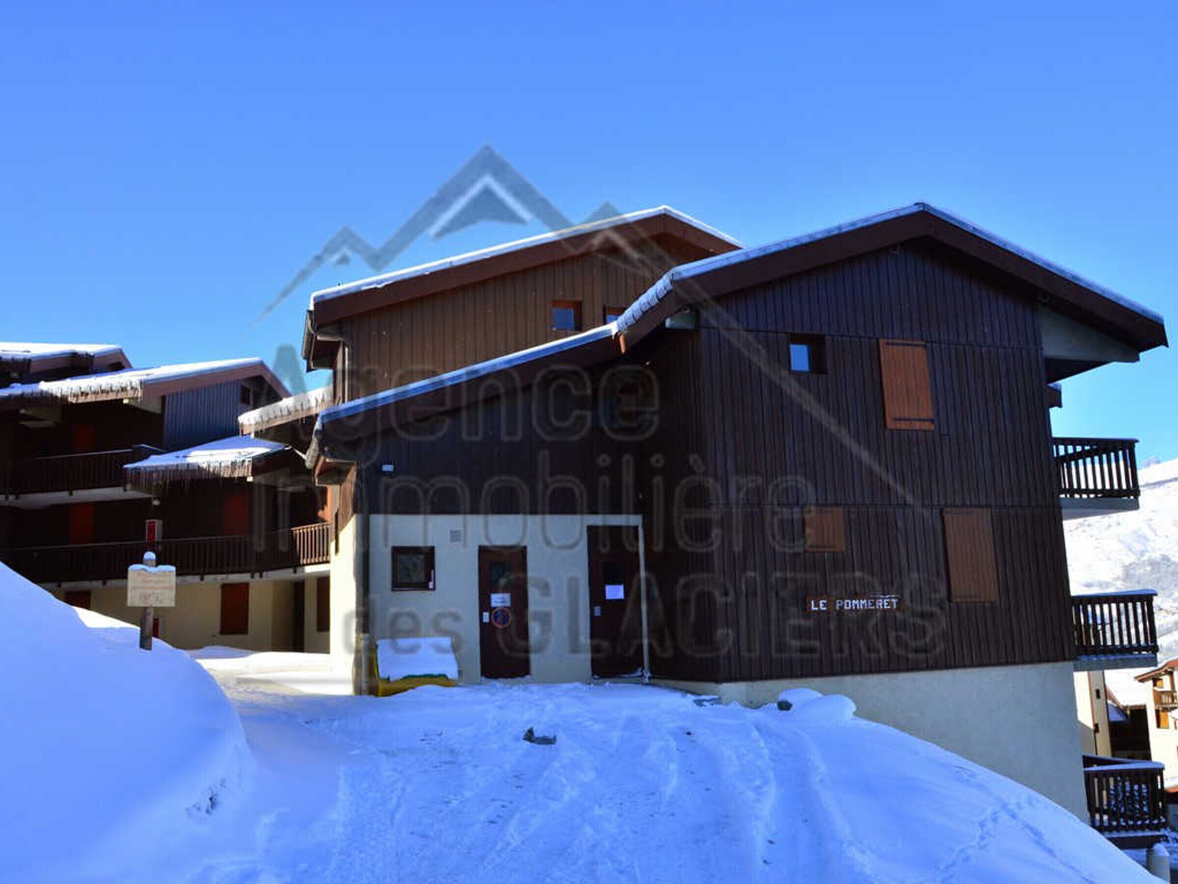 Un bâtiment de style chalet en bois, doté d’un balcon et entouré de neige.