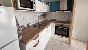 Eine kleine Küche mit Mikrowelle, Backofen, Spüle und Holzarbeitsplatte.