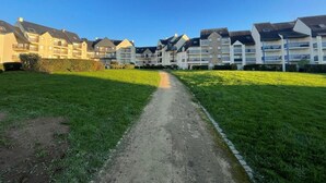 A pathway leading to a row of modern apartment buildings with balconies, surrounded by well-maintained grass. - Renovated T2 apartment, 5 people, pets allowed, Port Crouesty (Arzon)