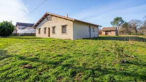 Une maison de plain-pied avec un toit en pente, un petit porche et une cour gazonnée.