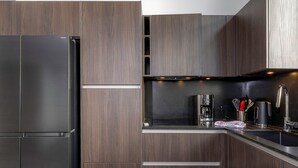 A modern kitchen with dark wood cabinets, stainless steel appliances, and a black countertop. - New penthouse for 12, 4 balconies, Alpages 1, Avoriaz (Avoriaz)