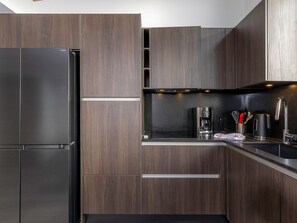 A modern kitchen with dark wood cabinets, stainless steel appliances, and a black countertop. - New penthouse for 12, 4 balconies, Alpages 1, Avoriaz (Avoriaz)