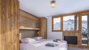 A bedroom with a bed, wooden paneling, a window with a mountain view, and a ceiling light. - New penthouse for 12, 4 balconies, Alpages 1, Avoriaz (Avoriaz)