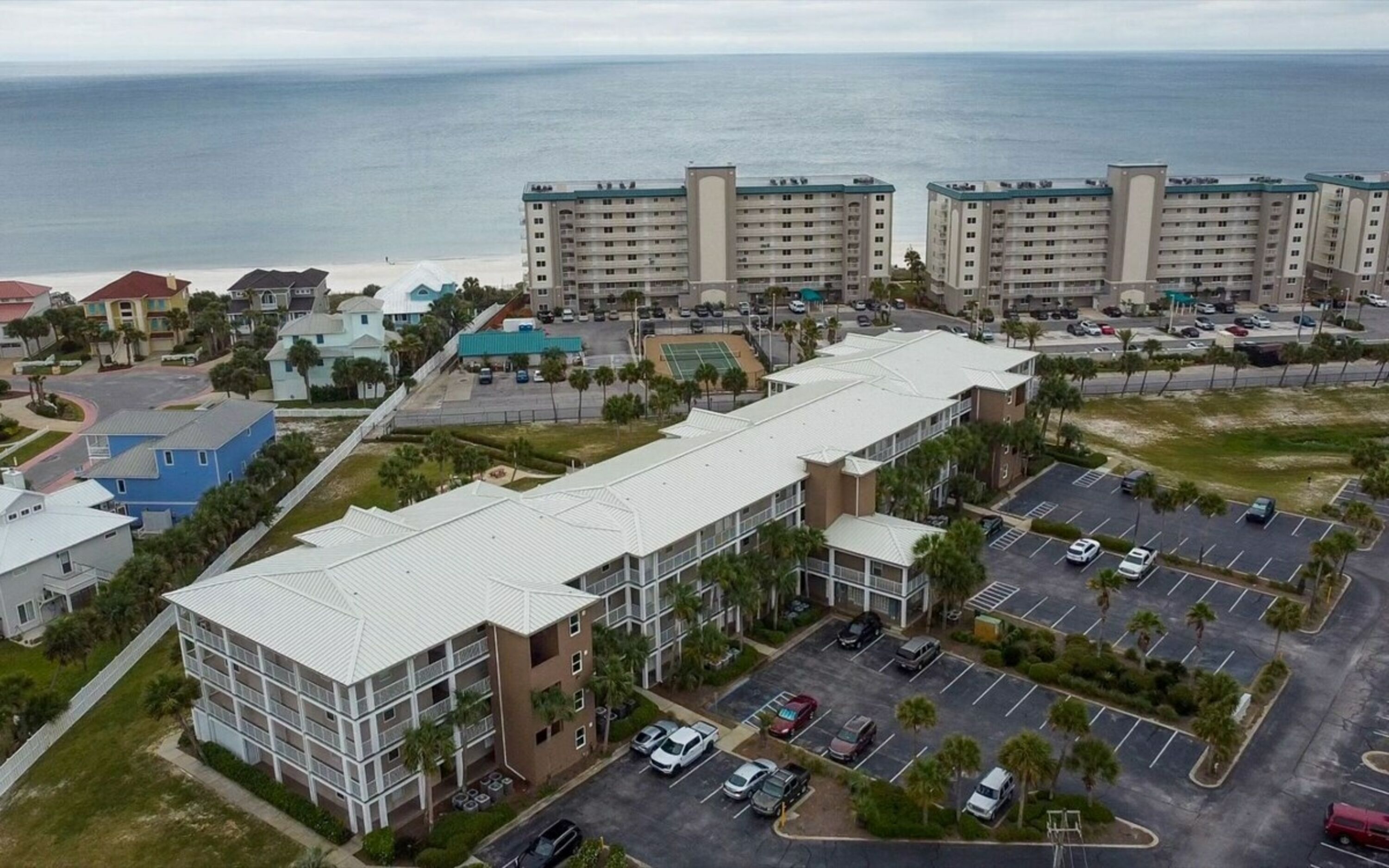 Um hotel com vários andares, estacionamento e vista para o oceano.