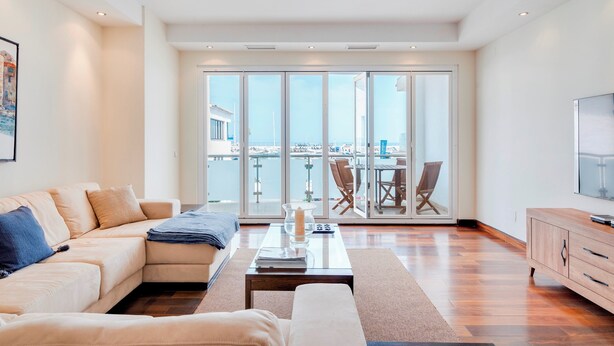 A spacious living room with a large sliding glass door leading to a balcony with a city view. - Puerto Banus Marina Apartment with Sea Views - Pass the Keys (Puerto  Banus)