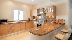 A modern kitchen with granite countertops, stainless steel appliances, wooden cabinets, and pendant lighting. - Puerto Banus Marina Apartment with Sea Views - Pass the Keys (Puerto  Banus)