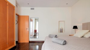 A hotel room with a large bed, wooden wardrobe, a mirror, and a bedside table with a lamp. - Puerto Banus Marina Apartment with Sea Views - Pass the Keys (Puerto  Banus)