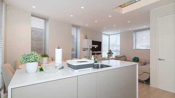A modern kitchen with a central island, built-in appliances, and a dining area with a table and chairs. - Modern Smart Home with Garden, close to Richmond - Pass the Keys (London)
