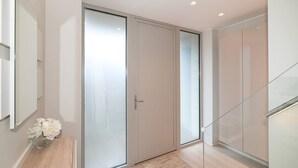 A modern interior with a sliding glass door, a wooden floor, and a small table with a vase of flowers. - Modern Smart Home with Garden, close to Richmond - Pass the Keys (London)