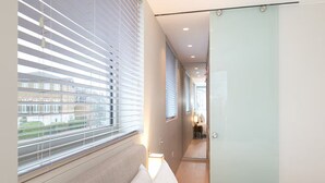 A modern bedroom with a large window, a bed, and a walk-in closet. - Modern Smart Home with Garden, close to Richmond - Pass the Keys (London)