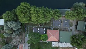 Vista aérea de una propiedad con zona de estacionamiento, un edificio de techo rojo y vegetación circundante.