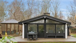 A modern, black-roofed structure with large windows, a deck, and a small outdoor seating area. - "Ordan" - 140m to the fjord by Interhome (Jægerspris)