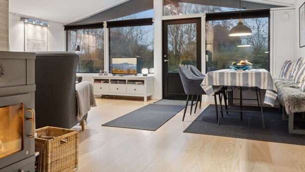 A modern interior with a dining area, a fireplace, and large windows offering a view of the outdoors. - "Ordan" - 140m to the fjord by Interhome (Jægerspris)