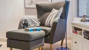 A modern living room with a grey armchair, a matching ottoman, a blue floor lamp, and a bookshelf with books. - "Ordan" - 140m to the fjord by Interhome (Jægerspris)