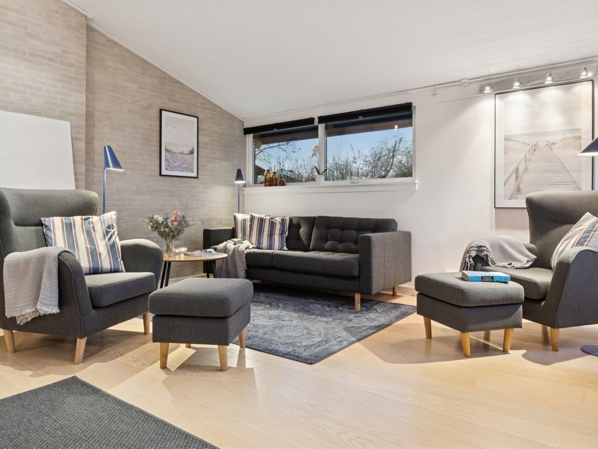 A modern living room with a grey sofa, two armchairs, a coffee table, and a rug.