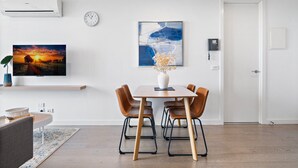 Un comedor moderno con una mesa de madera, cuatro sillas, un florero y un cuadro en la pared.