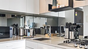 Una cocina moderna con electrodomésticos de acero inoxidable, un lavaplatos integrado y un bloque para cuchillos.