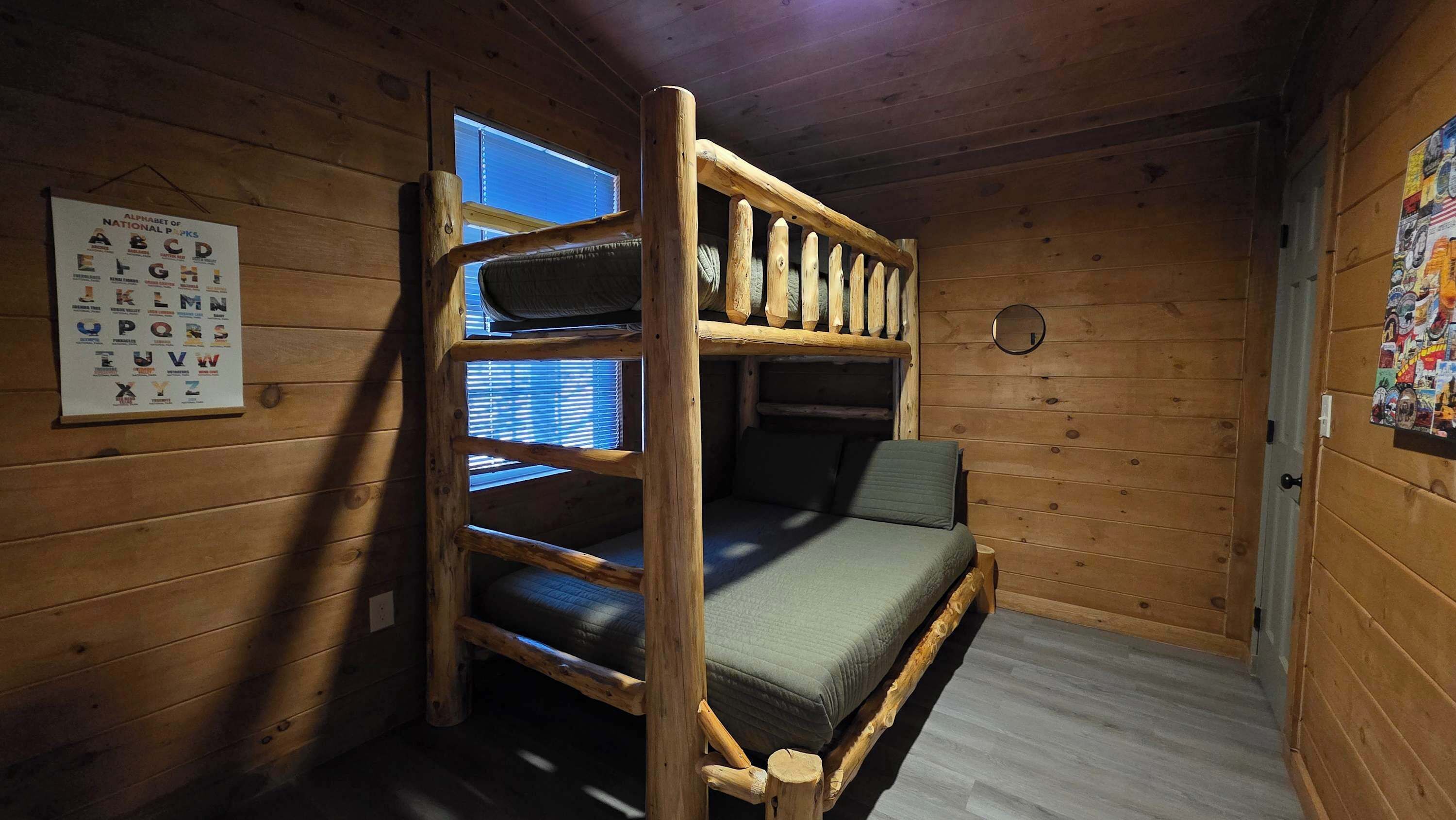 A bunk bed room with a wooden interior, a window, and a poster on the wall.