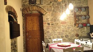 Un comedor rústico con pared de piedra, puerta de madera y una mesa cubierta con mantel rojo.