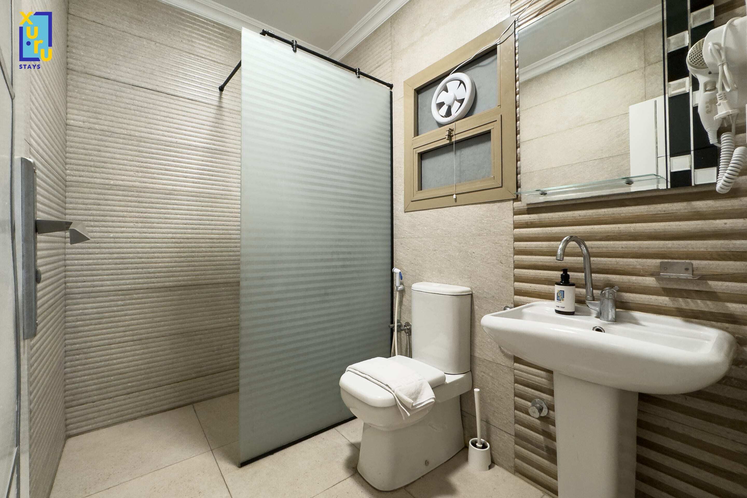 Un baño con inodoro, lavamanos y un perchero para toallas.