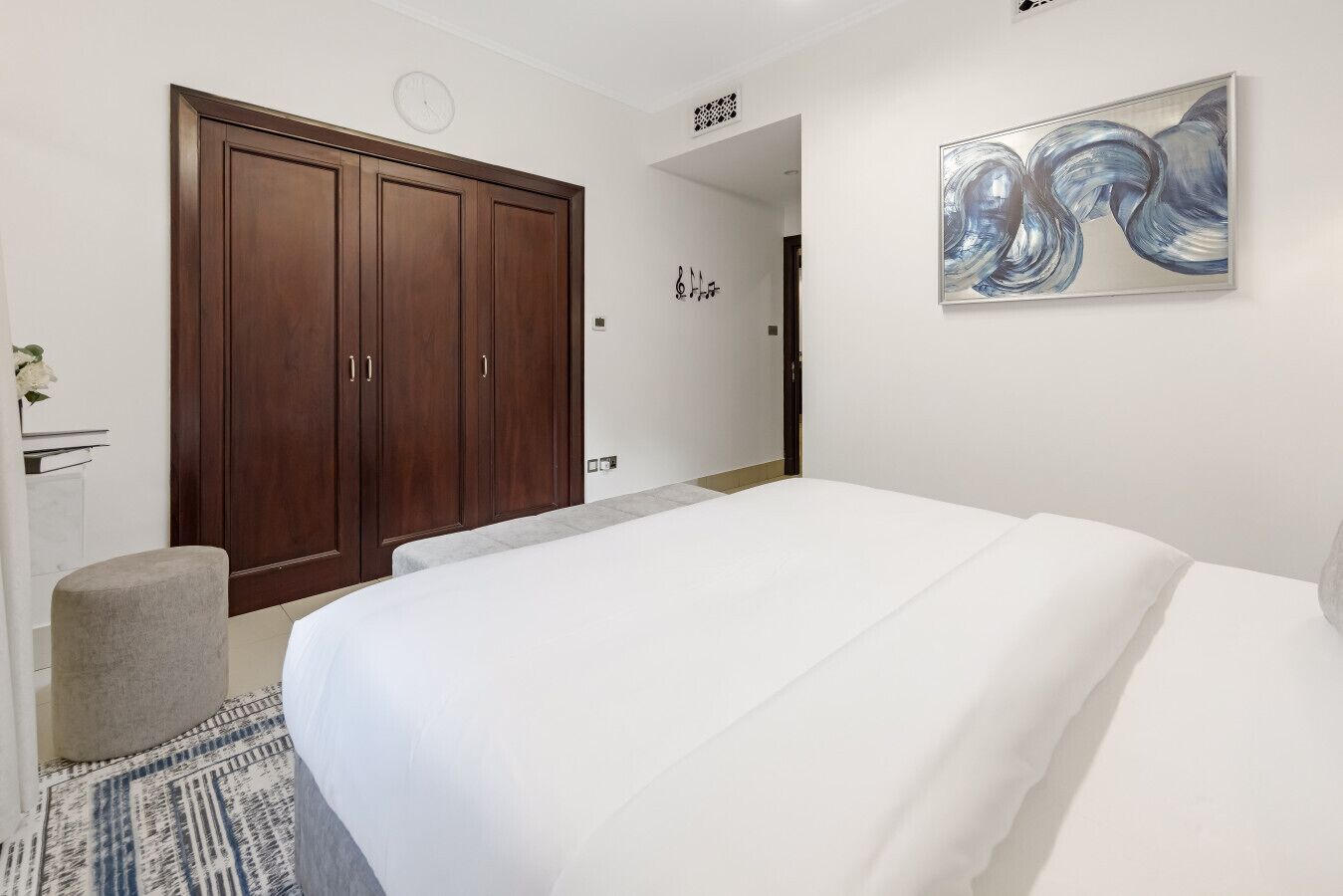 Une chambre avec un grand lit, une armoire en bois et un tableau abstrait accroché au mur.