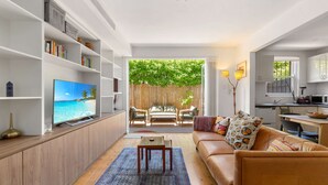 A modern living room with a TV, sofa, coffee table, and bookshelf. - Spacious Stay Near Shops & Cafes in Marrickville (Sydney)