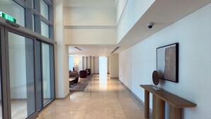 A spacious corridor with a polished floor, glass walls, and a wooden bench. - Durrani Homes - Alluring 5BR with Private Jacuzzi (Dubai)