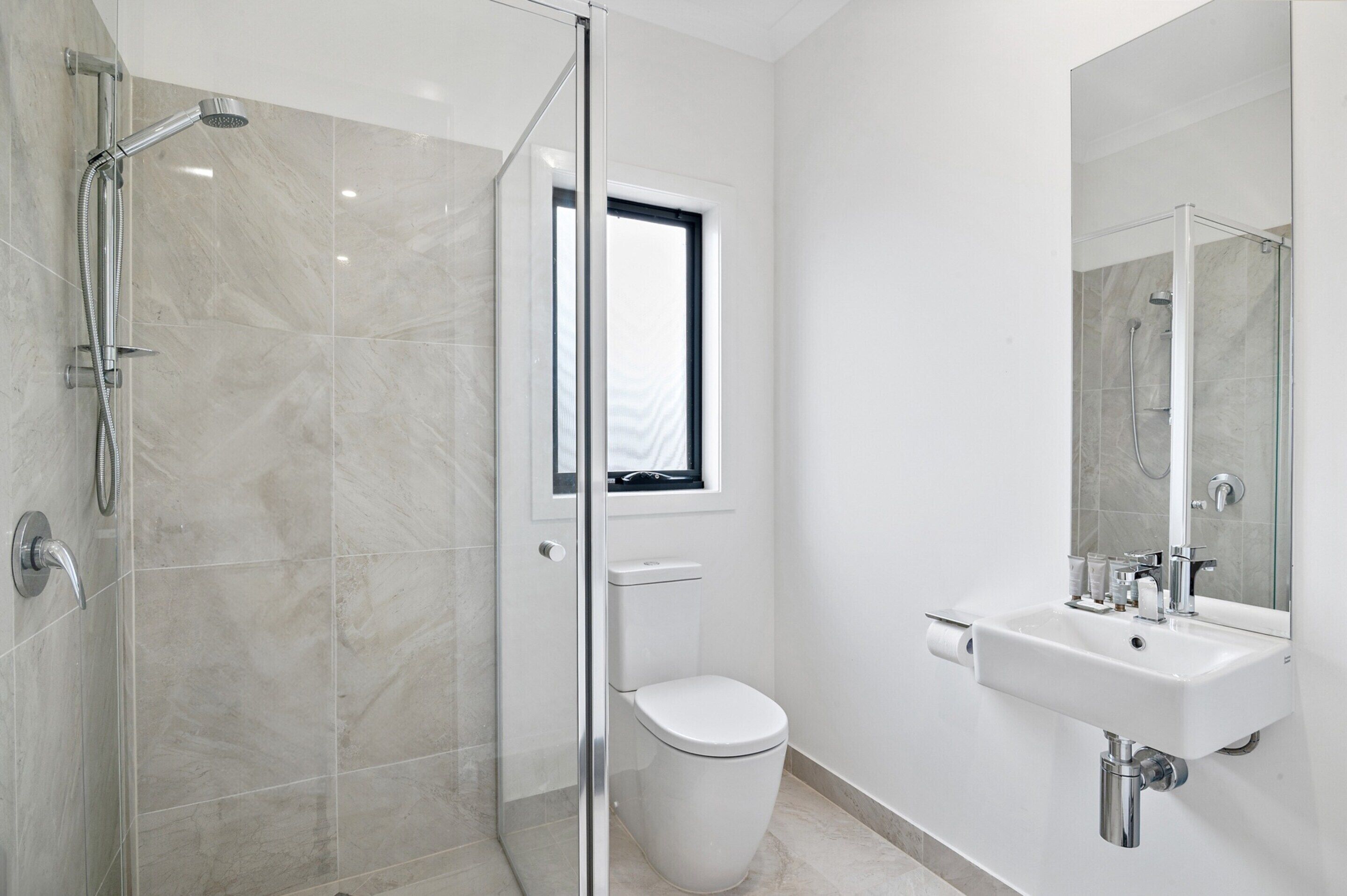 Une salle de bain moderne avec une douche à parois de verre, des toilettes et un lavabo avec un miroir.