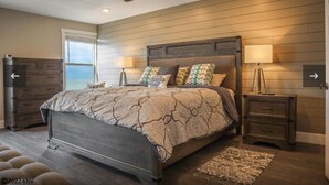 Ein Schlafzimmer mit einem großen Bett, zwei Nachttischen, einem Deckenventilator und Meerblick.
