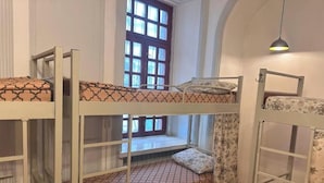 Bunk beds with patterned mattresses, a window with curtains, and a hanging light fixture. - Flora Hostel Baku (Baku)