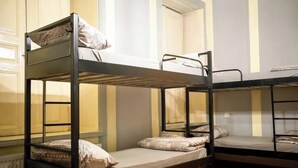 A bunk bed room with a wooden floor, a window with blinds, and a radiator. - Flora Hostel Baku (Baku)