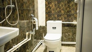 A bathroom with a white toilet, a sink, and a shower. - Flora Hostel Baku (Baku)