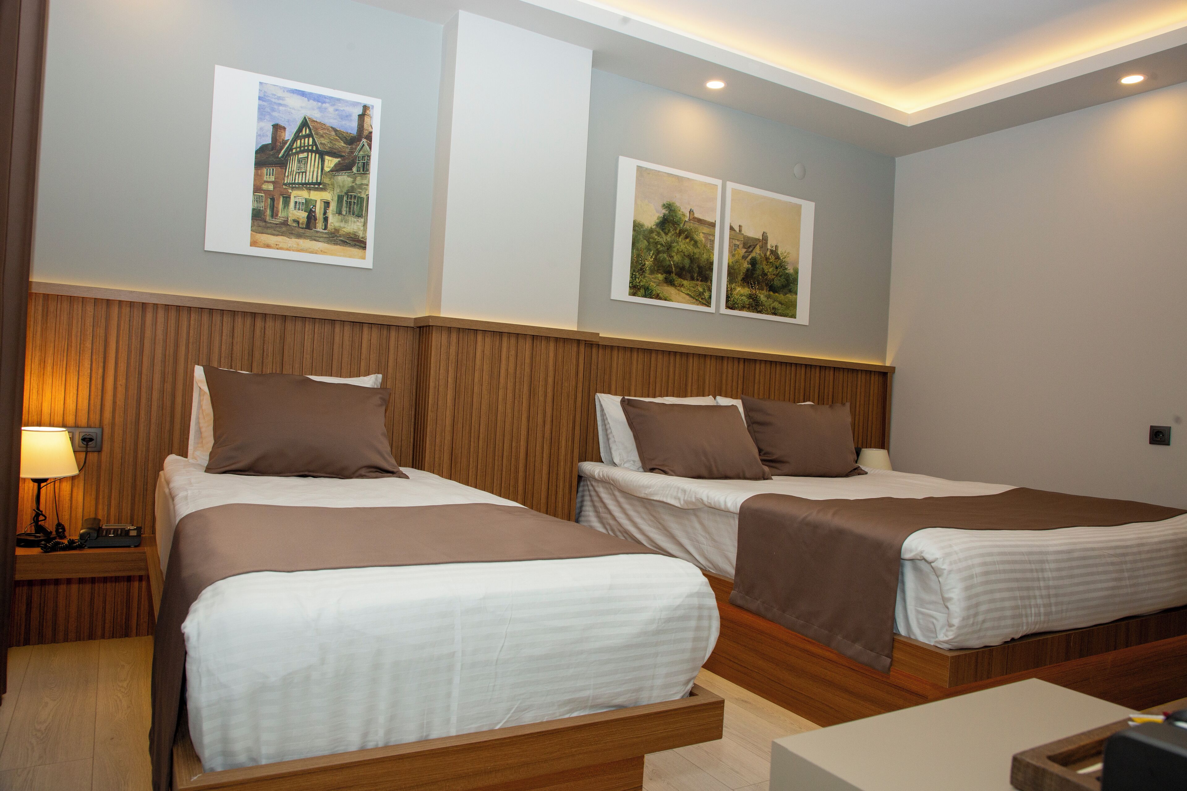 Une chambre d’hôtel avec deux lits, des têtes de lit en bois et une table de chevet avec une lampe.
