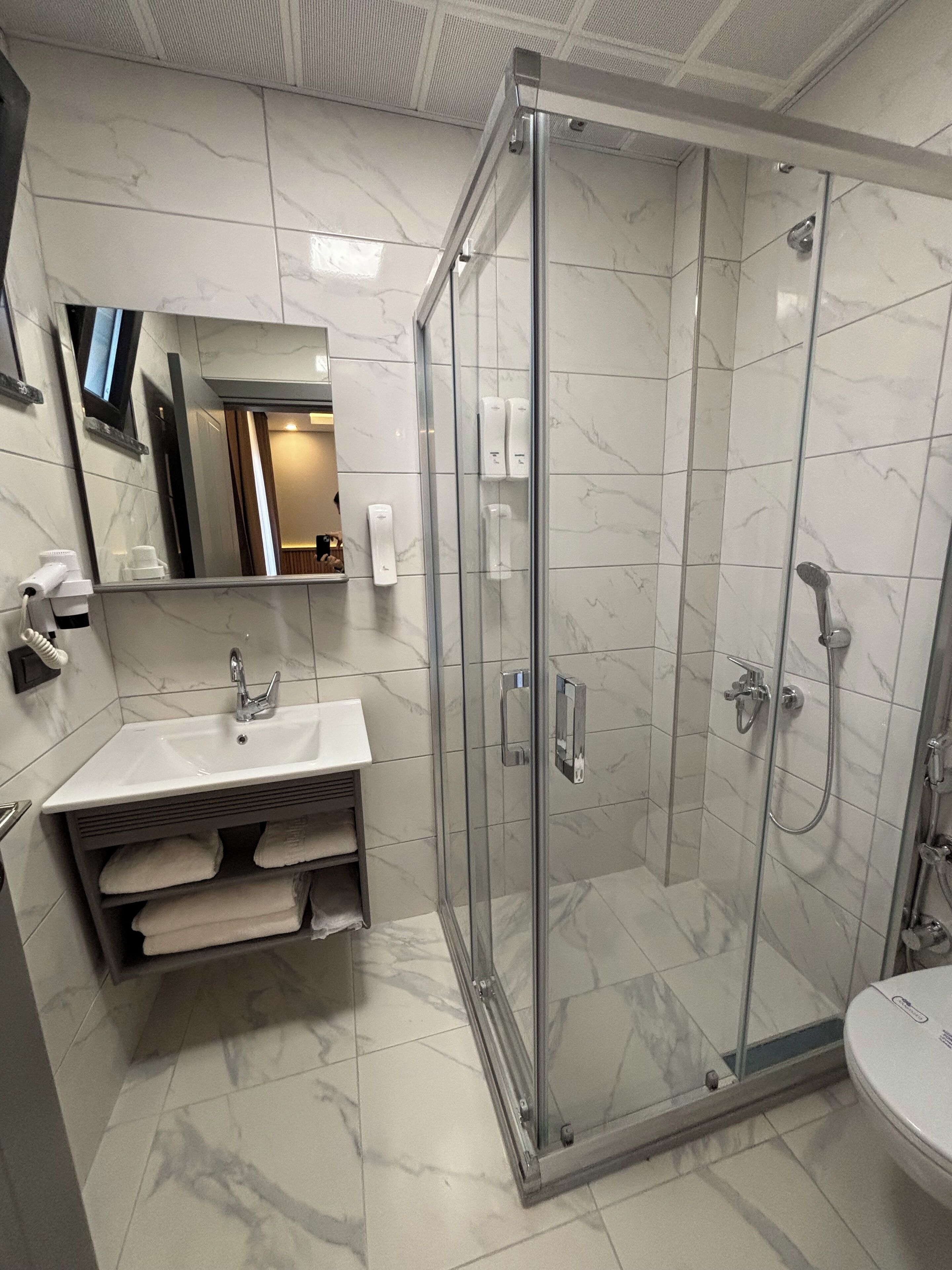 Un baño moderno con ducha de vidrio, un lavabo con toallero y un espejo sobre el lavabo.