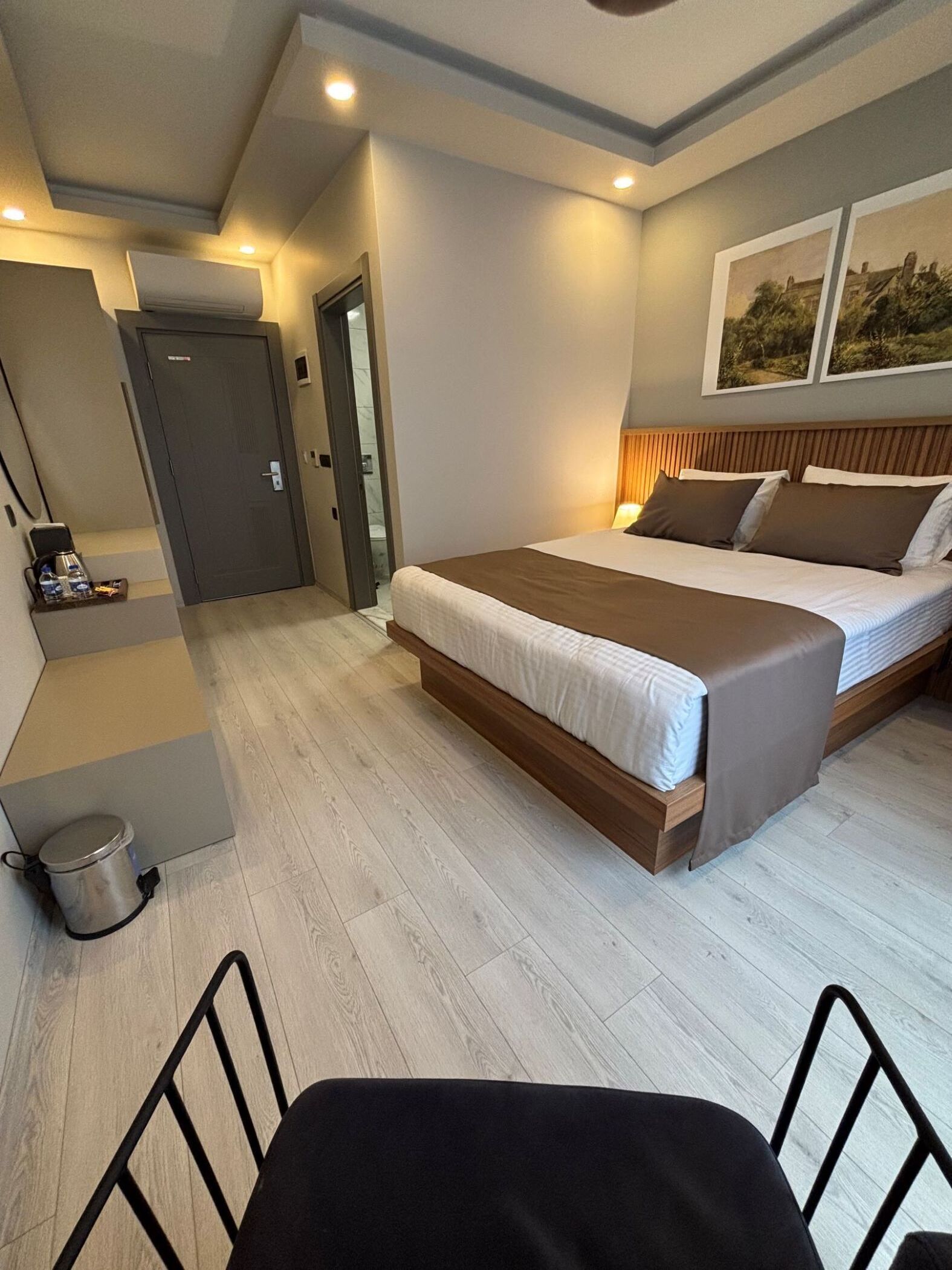 A hotel room with a bed, bedside table, and a small seating area.
