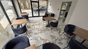 Un café moderno con suelo de mármol, sillas negras y mesas de madera.