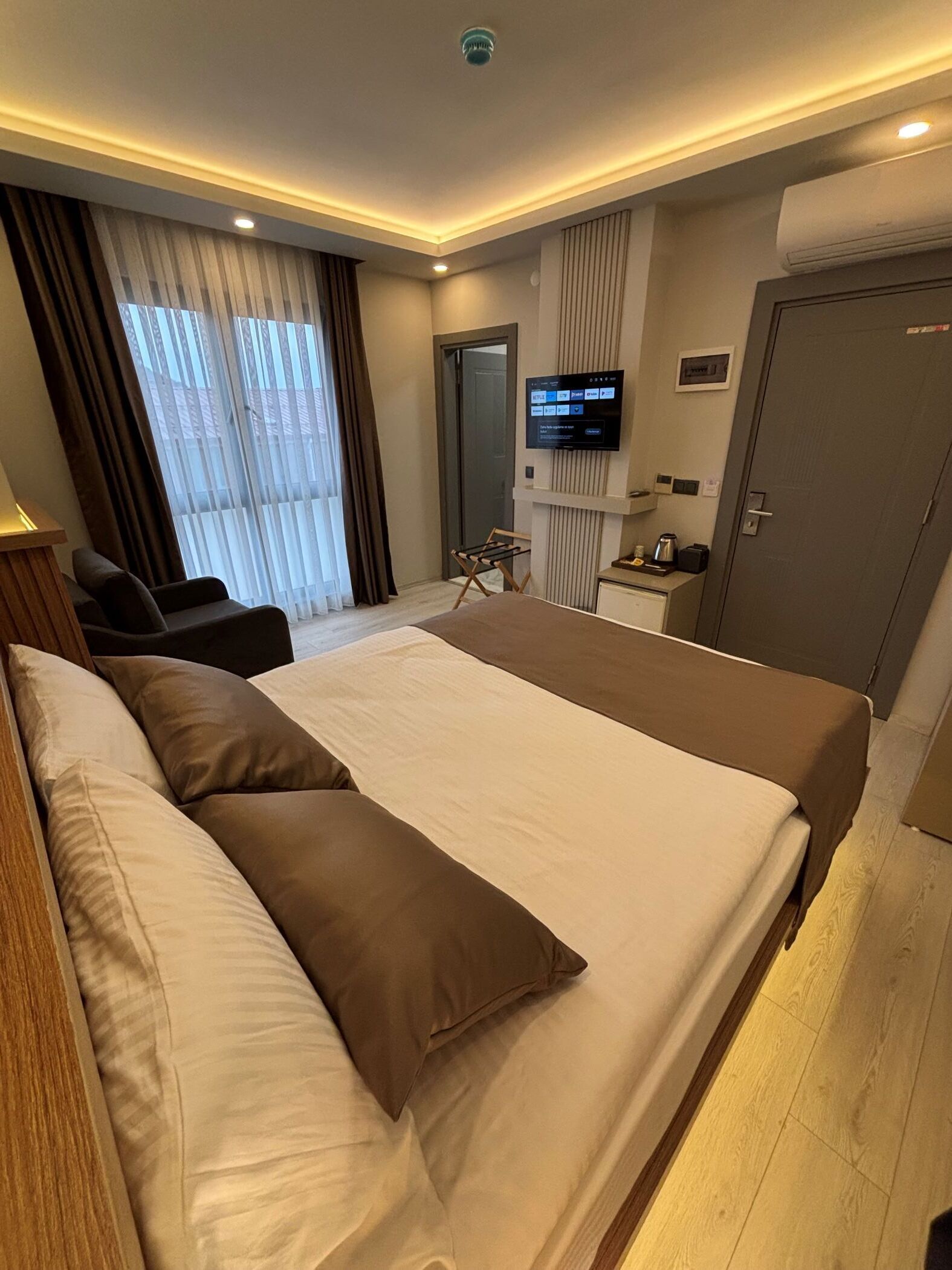 Une chambre d’hôtel avec un grand lit, un bureau, une chaise, une télévision et un appareil de climatisation.