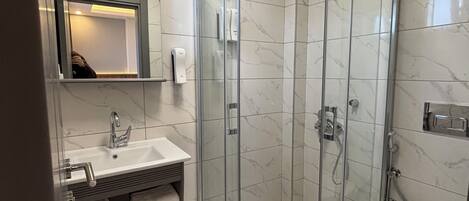 A modern bathroom with a glass-enclosed shower, a sink with a mirror, and a toilet.