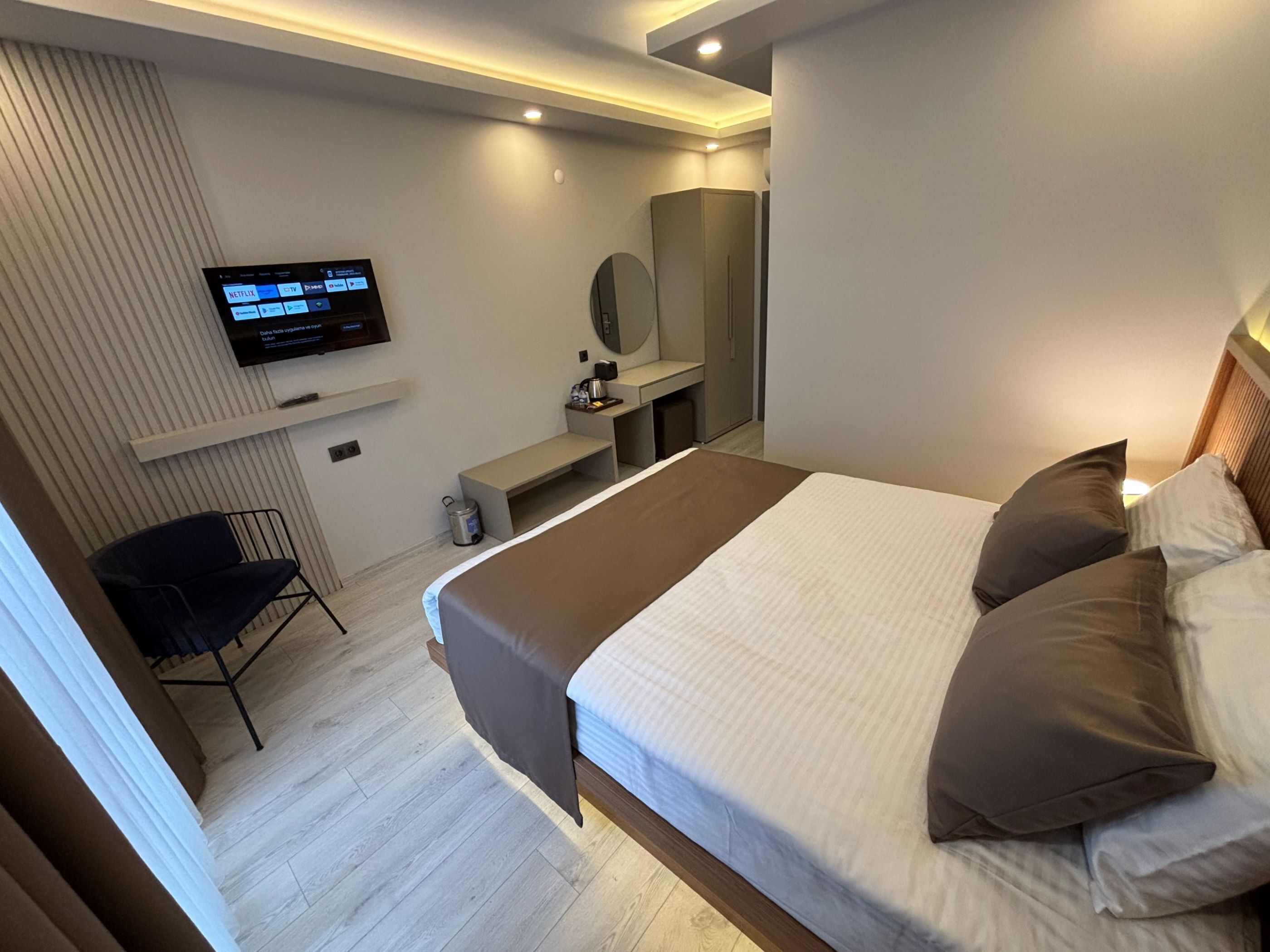 Une chambre d’hôtel moderne avec un grand lit, un téléviseur fixé au mur, un bureau et une chaise.