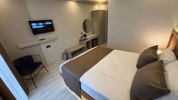 A modern hotel room with a large bed, a TV mounted on the wall, a desk, and a chair.