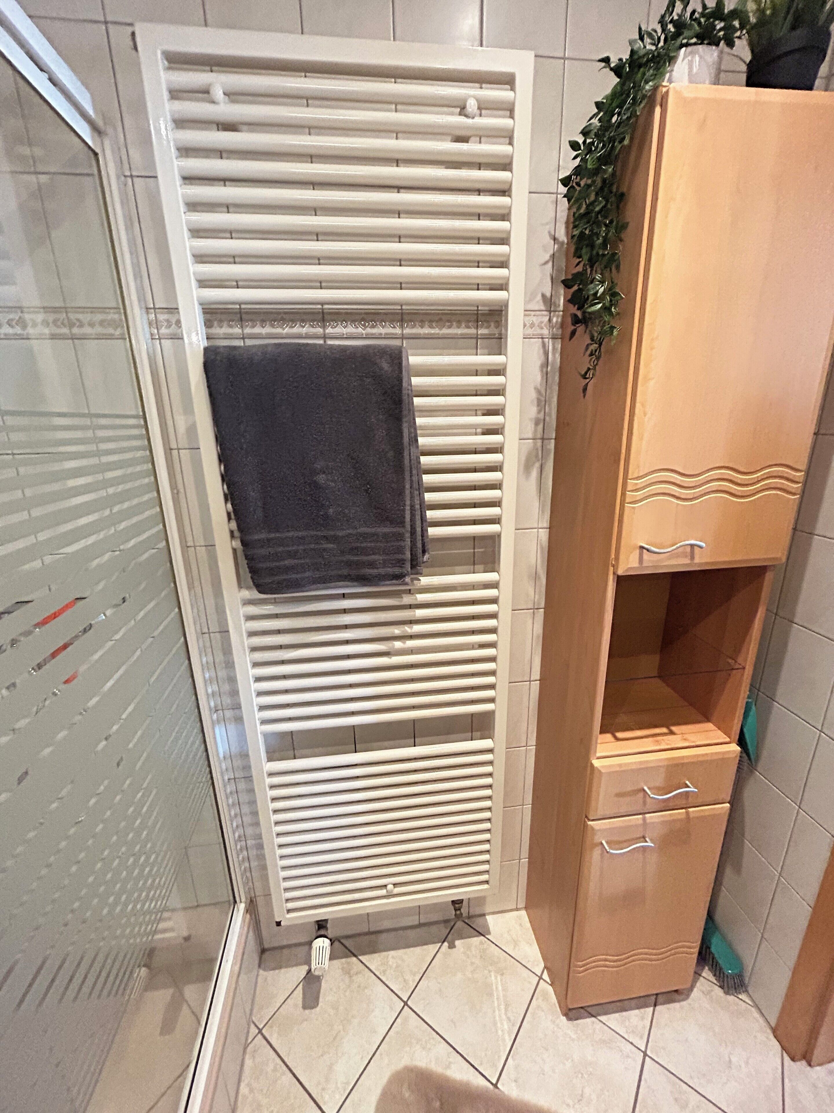 A bathroom with a towel rack, a wooden cabinet, and a tiled floor.