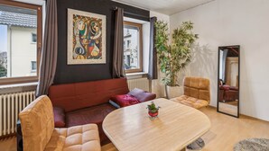 A modern living room with a sofa, a dining table, and a large mirror. - Cozy in the old town and nature (Trier)
