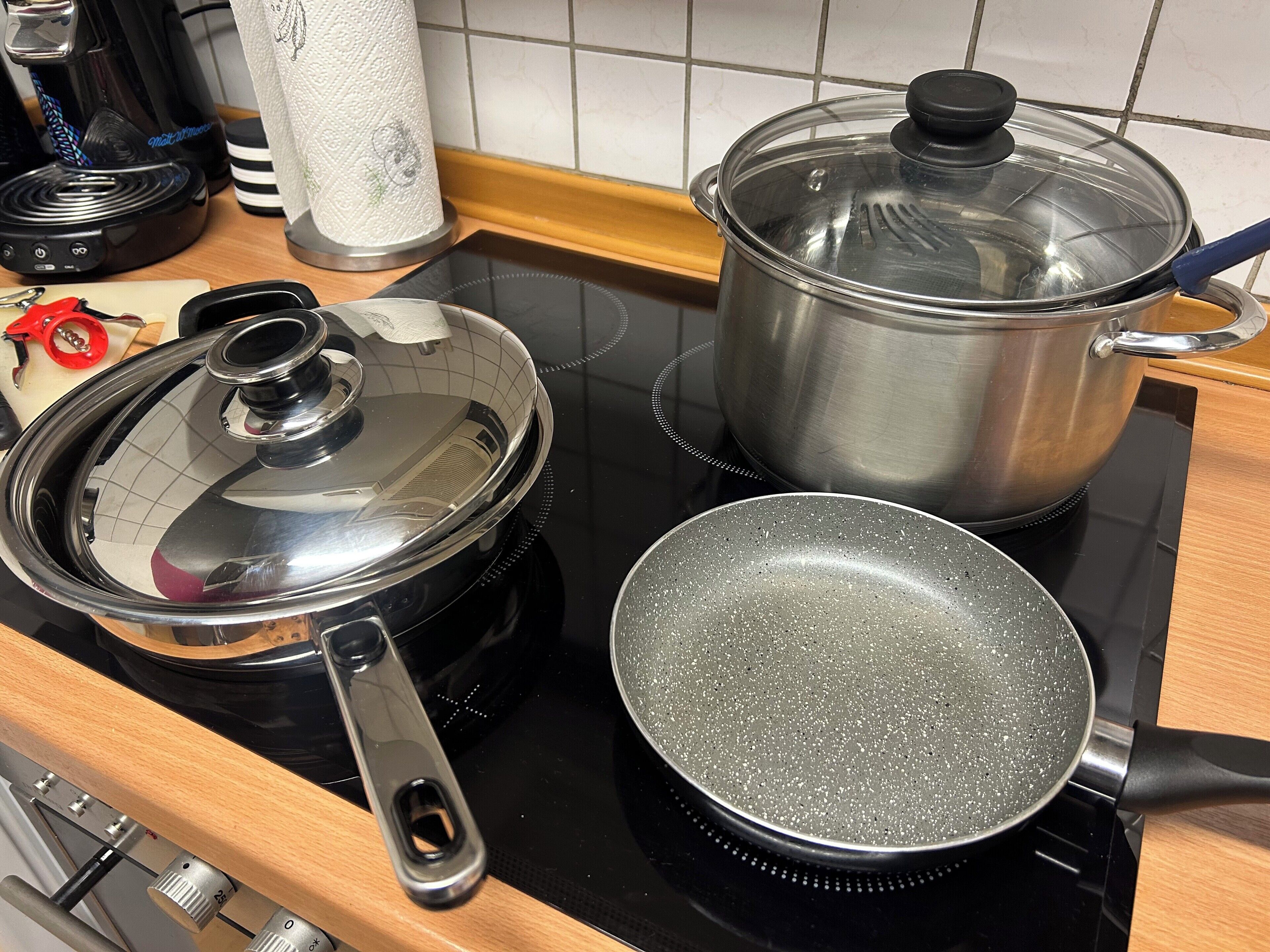 Eine Küche mit Herd, Bratpfanne, Topf mit Deckel und Wasserkocher.