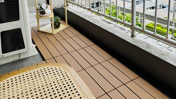 Un balcon donnant sur le paysage urbain, une petite étagère avec une plante et un appareil de ventilation.