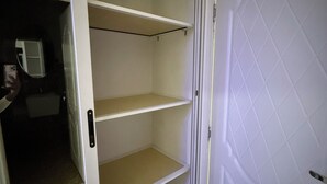 Een kamer met een witte deur, een spiegel met een witte lijst en een witte wandplank met drie planken.